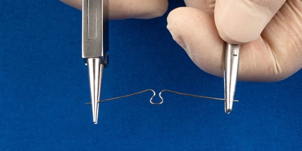 Nagelkorrekturspange aus Draht wird mit zwei Zangen geformt