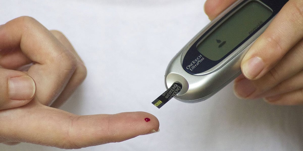Blutzuckermessung: Blutstropfen an der Fingerkuppe und Messgerät mit Teststreifen, Alltag bei Diabetes
