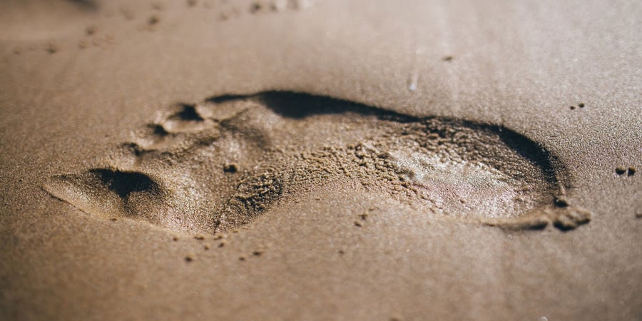 Abdruck eines nackten Fußes im Sand, Sinnbild für den Fußabdruck, den ein Podogramm aufzeichnet